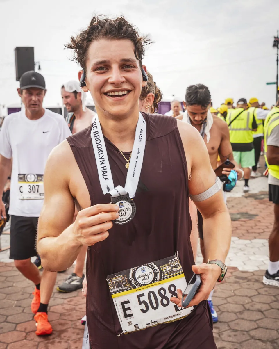 Anthony smiling with his Brooklyn Half medal after the race